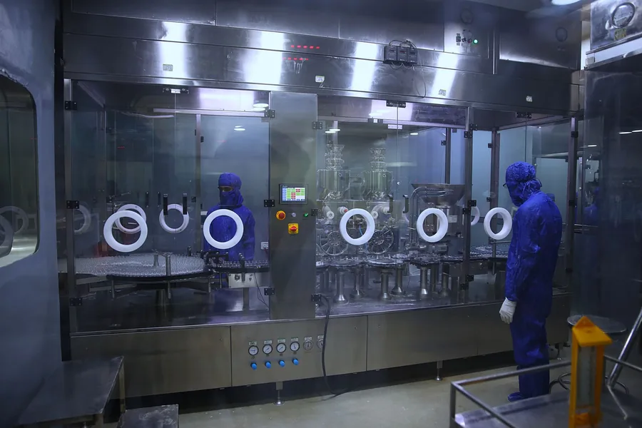Operators in protective gear beside a sterile pharmaceutical production line