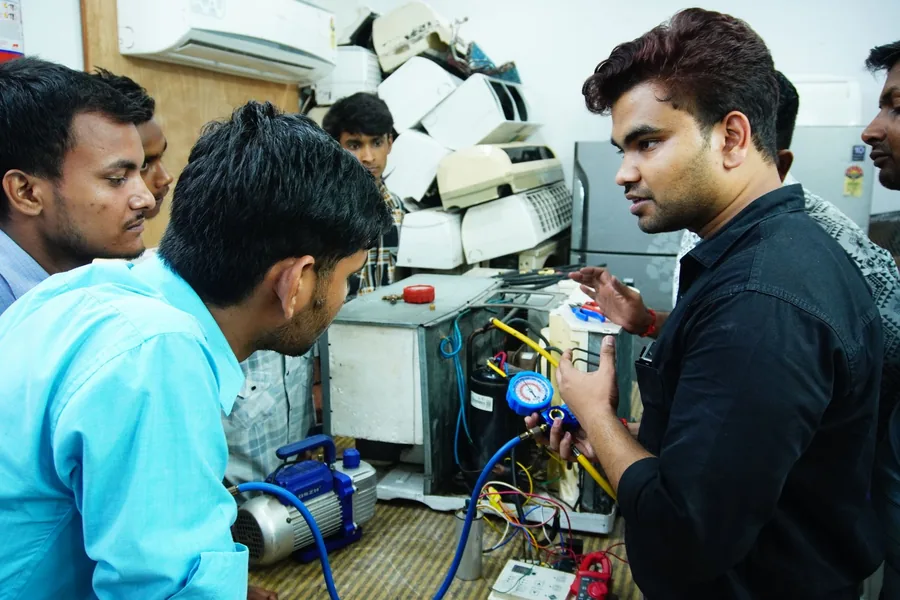 Technicians servicing a refrigeration unit with manifold gauges