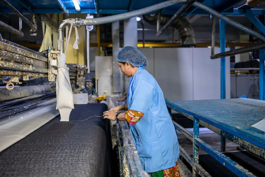 Worker at a fabric finishing machine in a textile mill